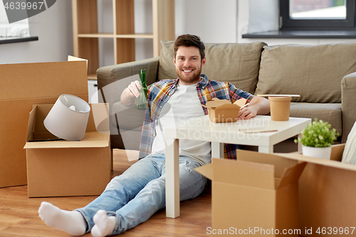 Image of smiling man drinking beer and eating at new home