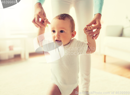 Image of happy baby learning to walk with mother help