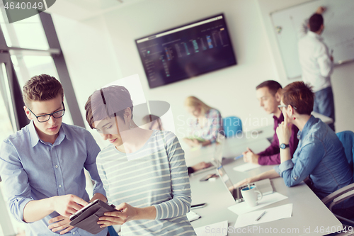 Image of Two Business People Working With Tablet in office