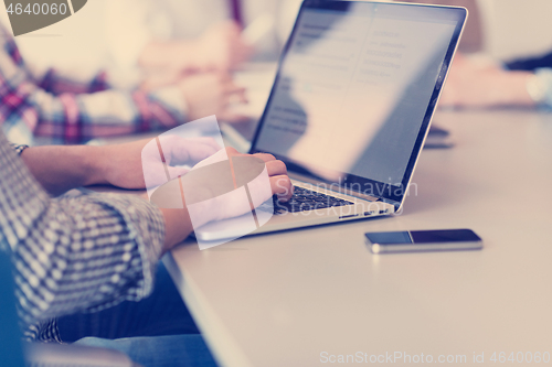 Image of close up of business man hands typing on laptop with team on mee