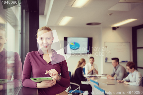 Image of blonde businesswoman working on tablet at office