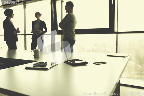 Image of close up of tablet, business people on meeting in background