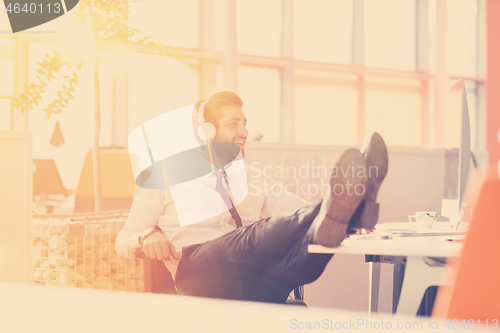 Image of relaxed young businessman first at workplace at early morning