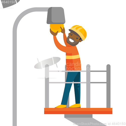 Image of African electrician changing a broken light bulb.