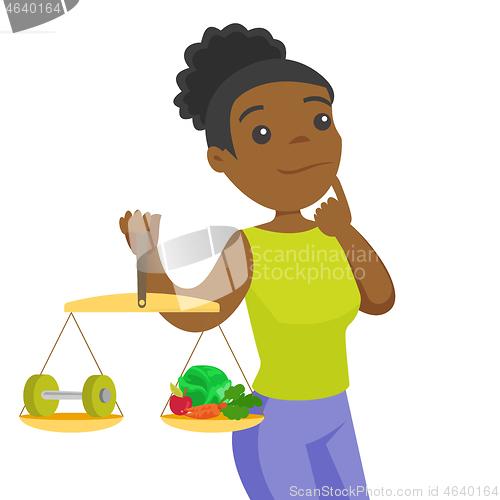 Image of African-american woman weighing food and dumbbell.