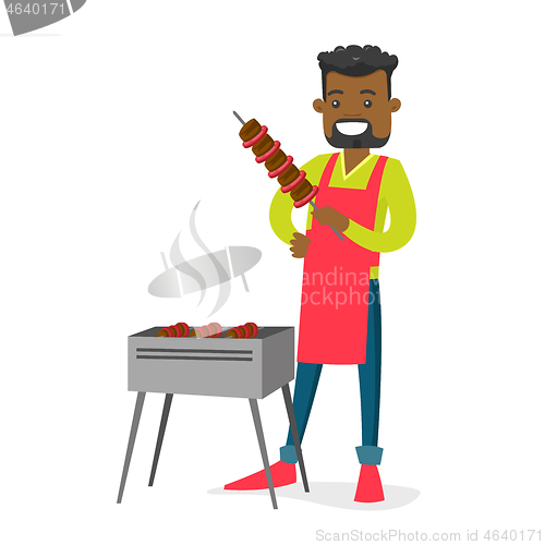 Image of Young african-american man cooking shashlik.