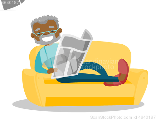 Image of Man laying on the couch and reading a newspaper.