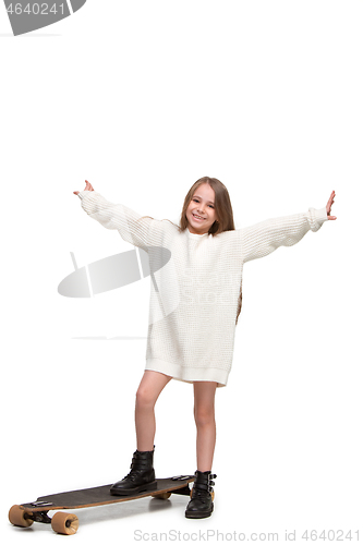 Image of Full length portrait of an adorable young girl riding a skateboard isolated against white background