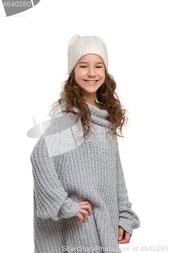Image of portrait of cute little kid in stylish knitted sweater looking at camera and smiling