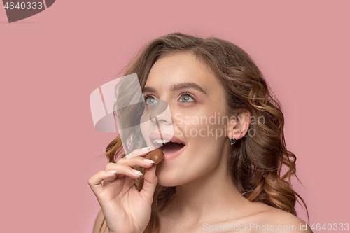 Image of beauty portrait of a cute girl in act to eat a chocolate candy
