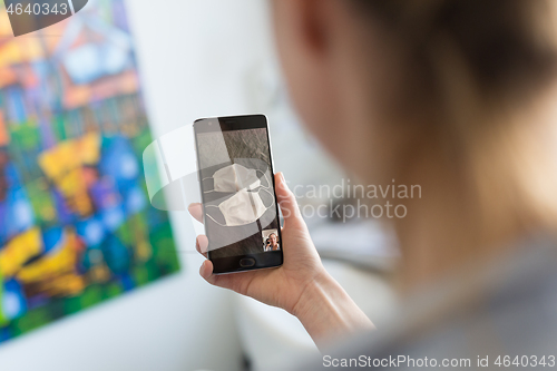 Image of Stay at home, social distancing lifestyle. Woman at home using social media on phone to learn about the use of masks and preventative measures during corona virus pandemic.