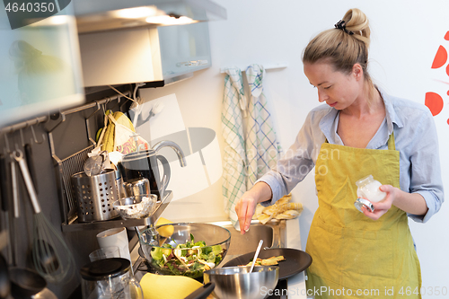 Image of Stay at home and social distancing. Woman in her casual home clothing working remotly from kitchen dining table. Video chatting using social media with friend, family, business clients or partners