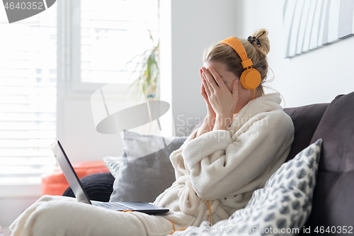 Image of Stressed business woman in her casual home bathrobe working remotly from her living room during corona virus pandemic crisis. Stay at home and social distancing