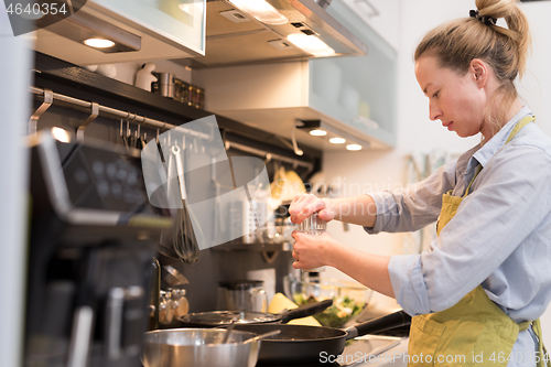 Image of Stay at home and social distancing. Woman in her casual home clothing working remotly from kitchen dining table. Video chatting using social media with friend, family, business clients or partners