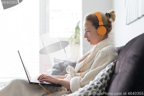 Image of Stay at home and social distancing. Woman in her casual home bathrobe working remotly from her living room. Video chatting using social media with friend, family, business clients or partners