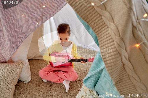 Image of little girl playing guitar in kids tent at home