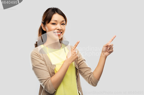 Image of happy asian woman pointing fingers up