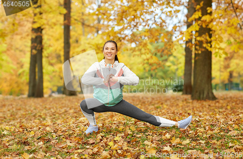 Image of young woman doing sports at autumn park