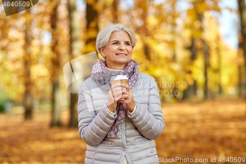 Image of senior woman drinking coffee in autumn park