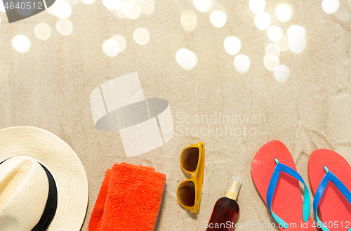 Image of straw hat, flip flops and sunglasses on beach sand