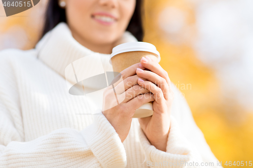 Image of happy young woman drinking coffee in autumn park