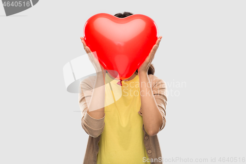 Image of woman with face behind red heart shaped balloon