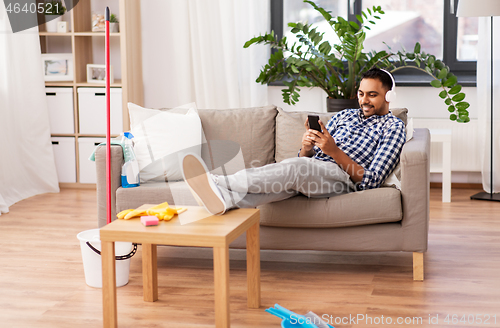 Image of indian man in headphones after cleaning home