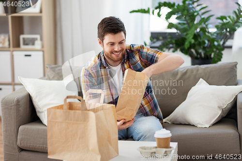Image of smiling man unpacking takeaway food at home