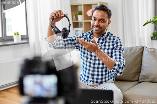 Image of male blogger with headphones videoblogging at home