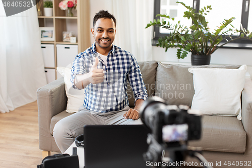 Image of male blogger with camera videoblogging at home