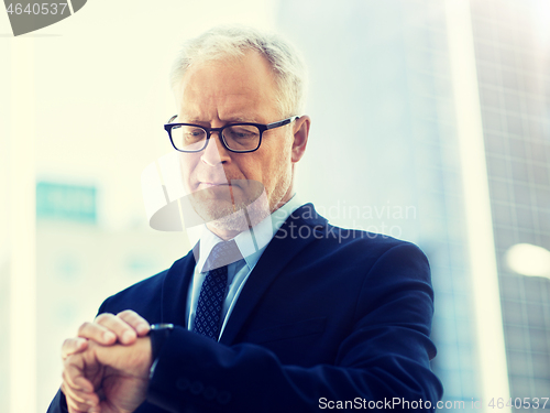 Image of senior businessman checking time on his wristwatch