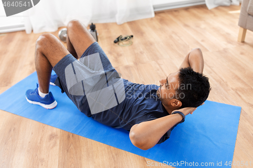 Image of indian man making abdominal exercises at home