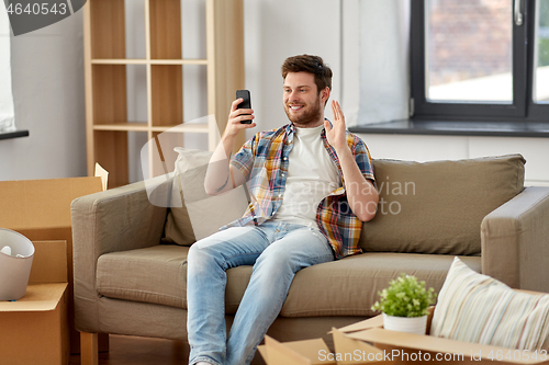Image of man with smartphone having video call at new home