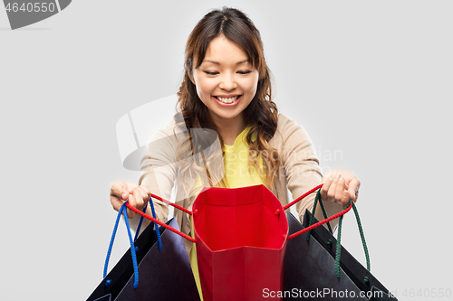 Image of happy asian woman with open shopping bags