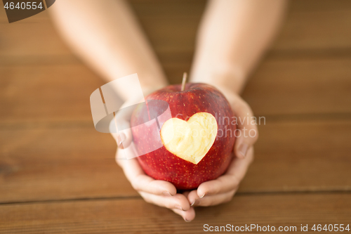 Image of close up of hands holding apple with carved heart