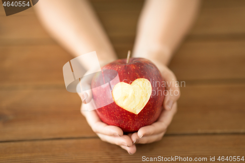 Image of close up of hands holding apple with carved heart