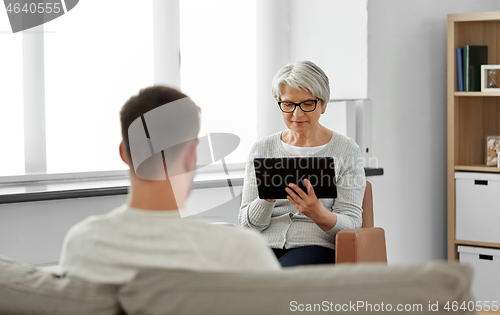 Image of senior psychologist with tablet pc and patient