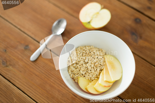 Image of oatmeal in bowl with apple and spoon on table