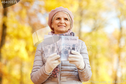 Image of senior woman with city guide at autumn park