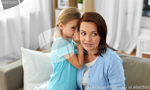 Image of daughter whispering secret to mother at home