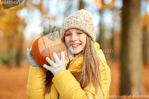 Image of happy girl with pumpkin at autumn park