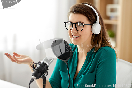 Image of woman with microphone recording podcast at studio