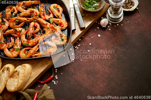 Image of Grilled prawns in cast iron grilling pan with fresh lemon, parsley, chili, garlic white wine sauce