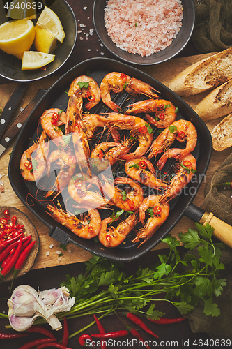 Image of Tasty appetizing roasted shrimps prawns with spices on pan with ingredients on rusty background