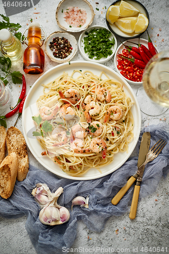 Image of Spaghetti with shrimps on white ceramic plate and served with glass of white wine