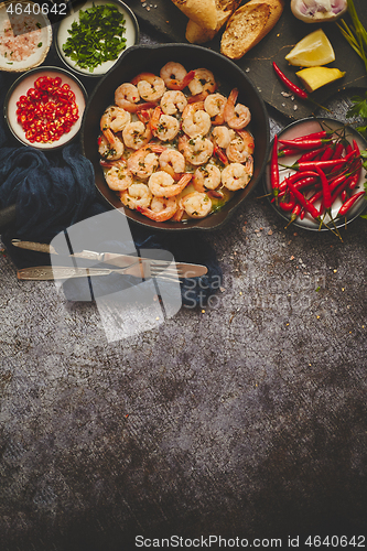 Image of Grilled shrimps in cast iron grilling pan with fresh lemon, parsley, chili, garlic white wine sauce