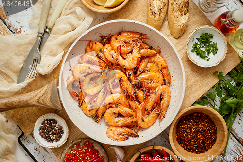 Image of Roasted Prawns on frying pan served on white wooden cutting board