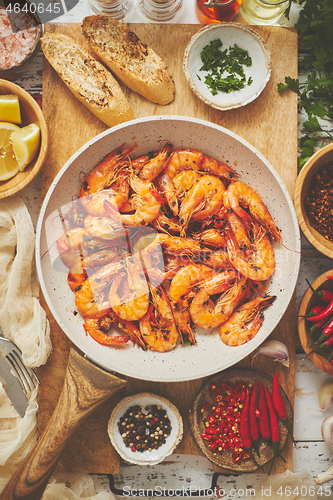 Image of Traditional fried tiger prawn with garlic bread as top view served in a white frying pan