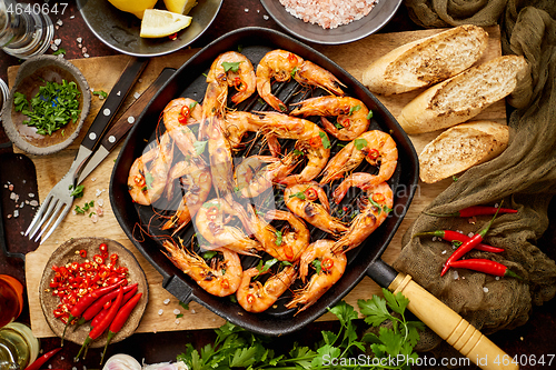 Image of Tasty appetizing roasted shrimps prawns with spices on pan with ingredients on rusty background