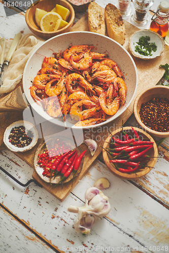 Image of Traditional fried tiger prawn with garlic bread as top view served in a white frying pan